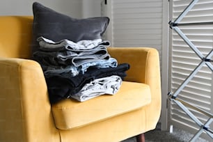 a yellow chair with a pile of clothes on it