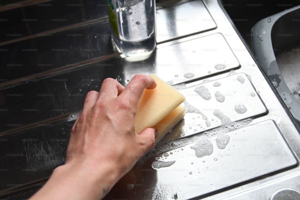a person cleaning a stove with a sponge