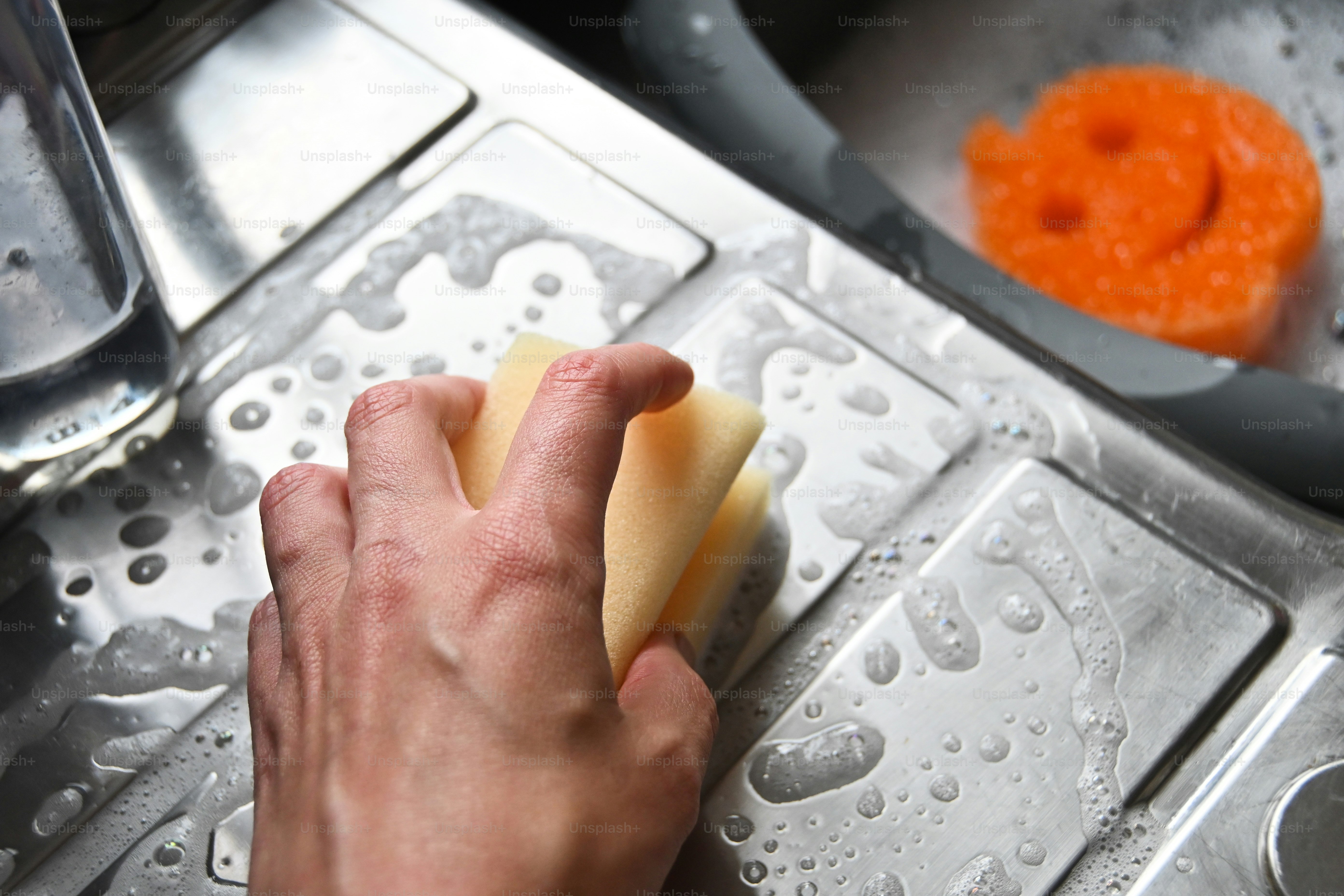 a person is cleaning a kitchen sink with a sponge
