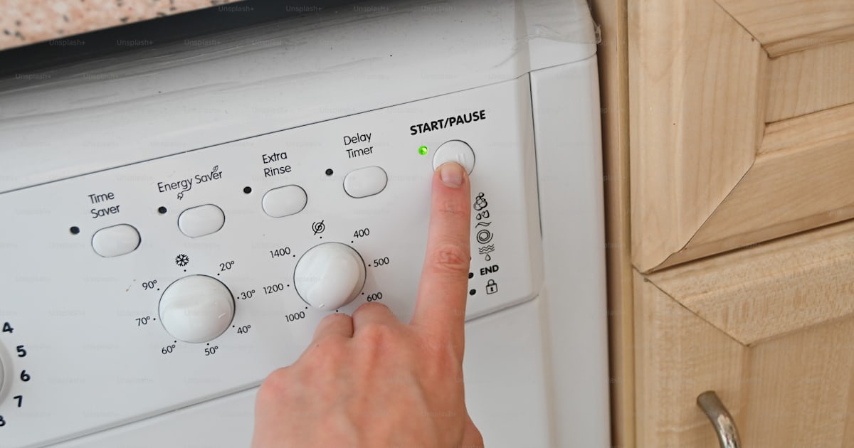 Une personne appuyant sur des boutons sur une machine à laver photo ...