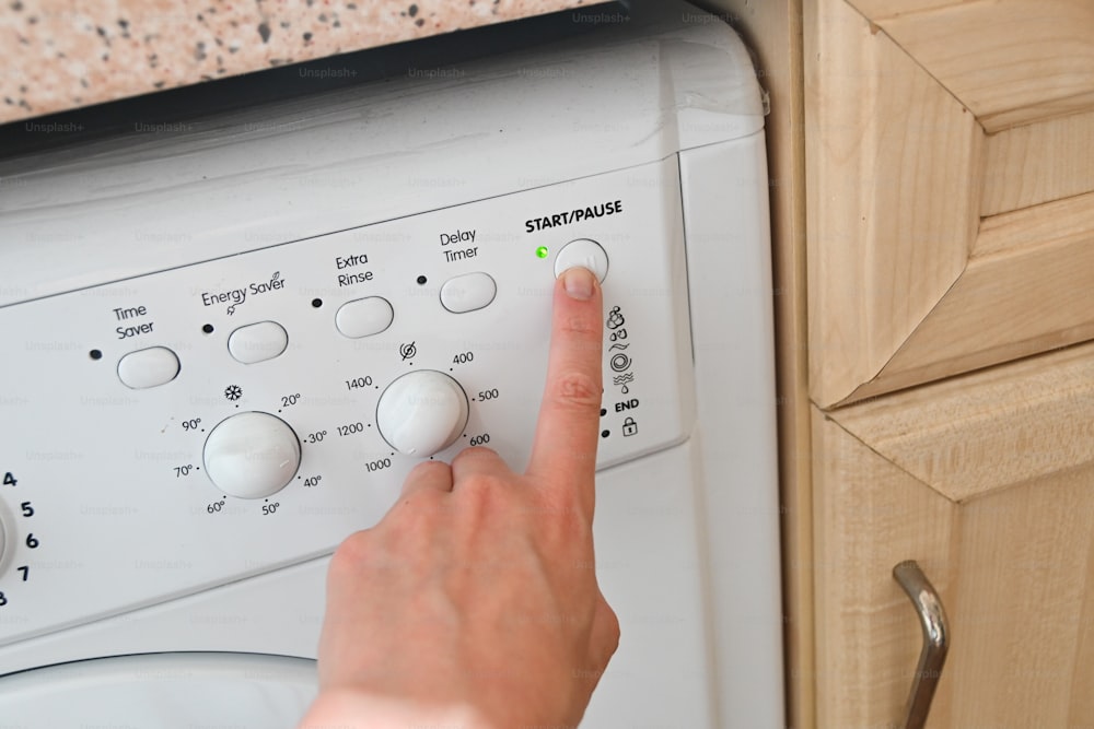 uma pessoa pressionando botões em uma máquina de lavar roupa