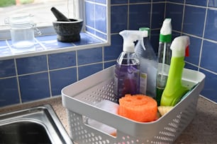 a white basket filled with cleaning products next to a sink