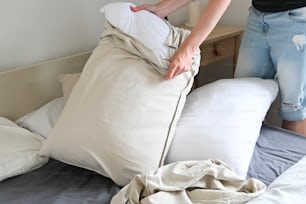 une personne mettant un oreiller sur un lit