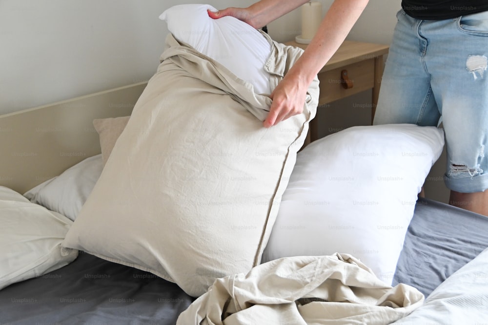 uma pessoa colocando um travesseiro em cima de uma cama