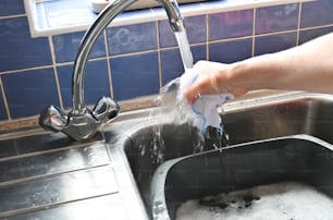 a person washing their hands in a kitchen sink