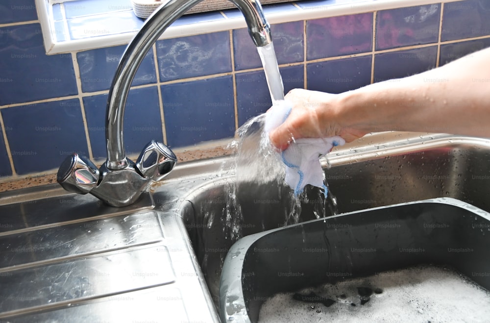 a person washing their hands in a kitchen sink
