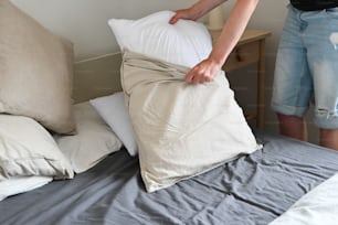 a person putting a pillow on top of a bed