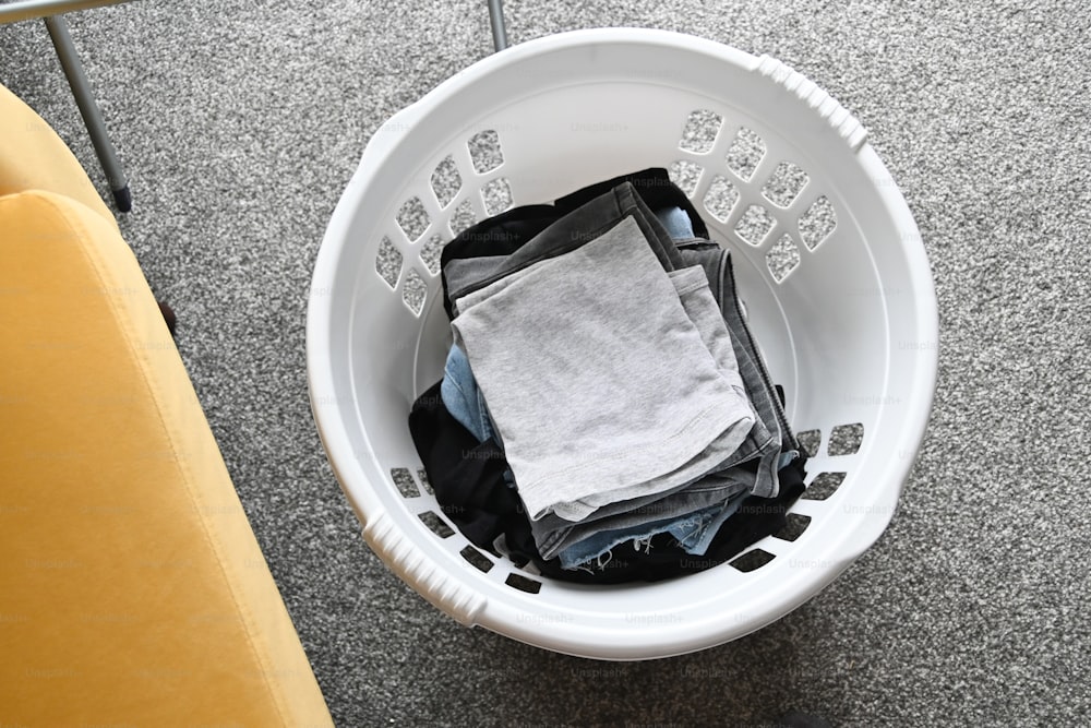 a white bucket filled with clothes on top of a floor