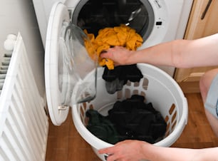 uma pessoa colocando roupas em uma máquina de lavar
