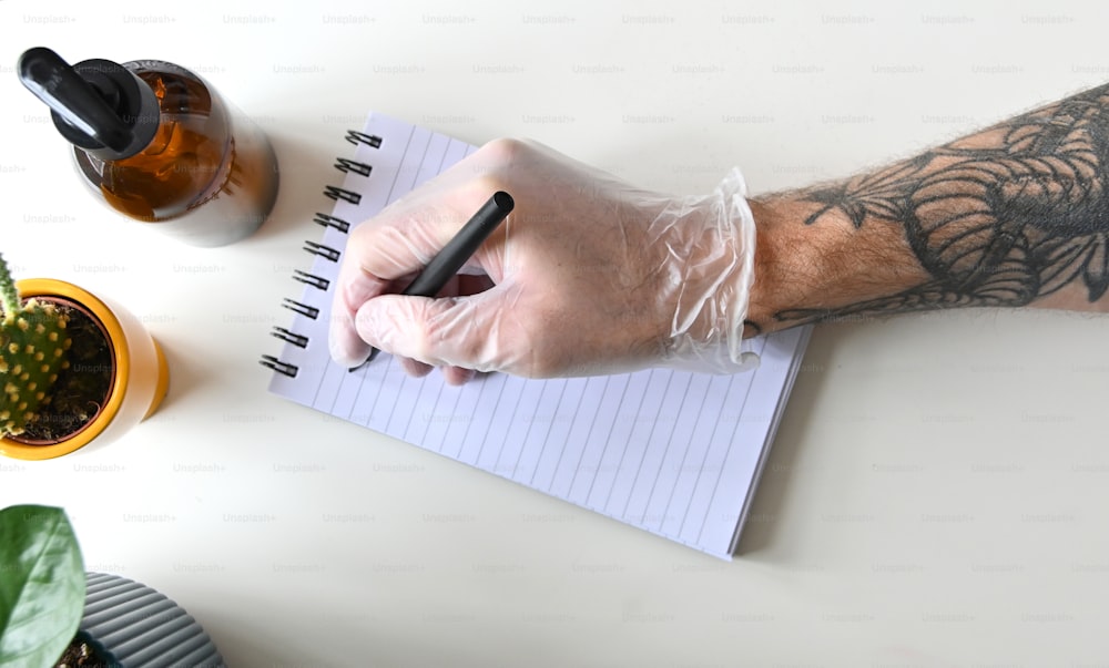 팔에 문신을 한 남자가 메모장에 글을 쓰고 있다