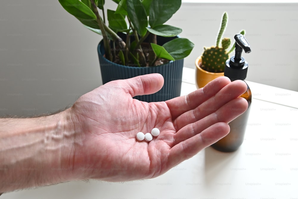 a person holding out their hand with some pills in it