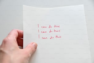 a person holding a piece of paper with writing on it