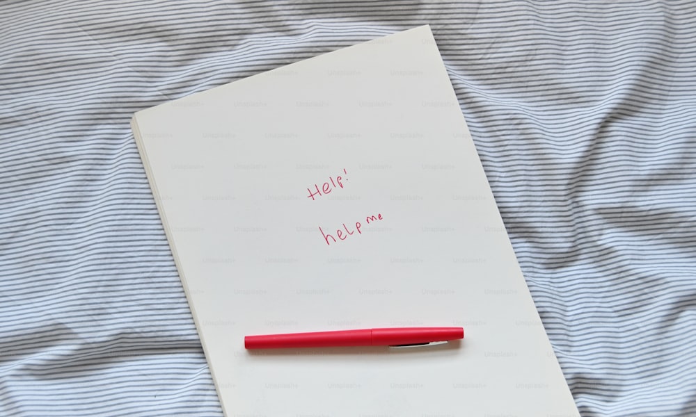 a note pad with a red pen on top of it