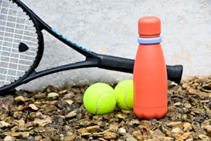 a tennis racket and two tennis balls on the ground