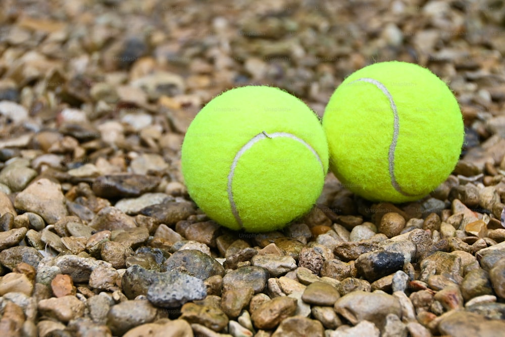 two tennis balls sitting on top of a pile of rocks