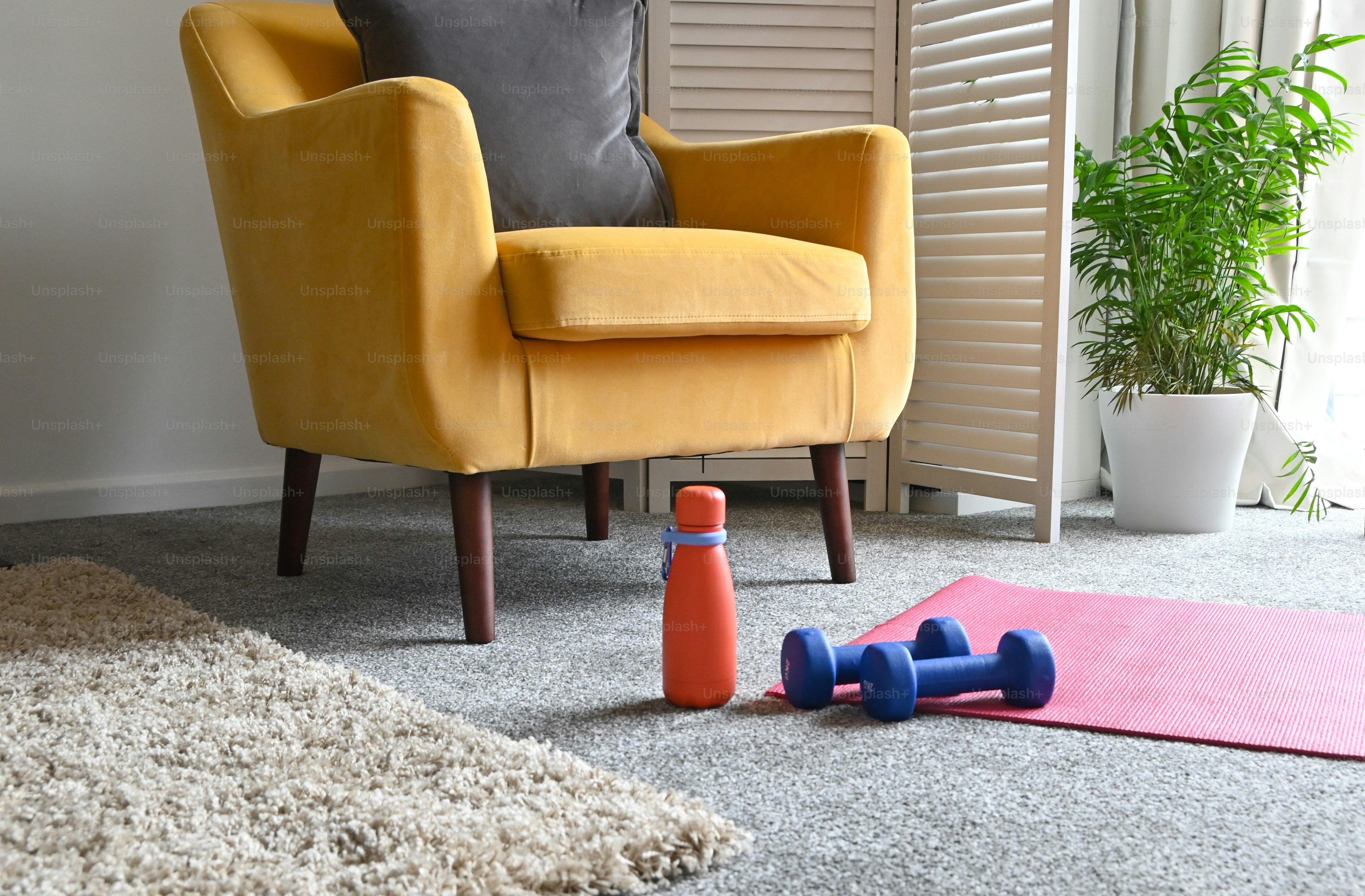 a yellow chair sitting next to a pink rug