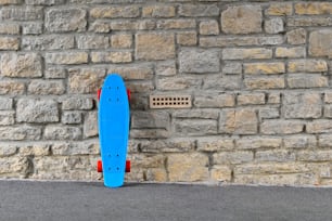 un monopatín azul apoyado contra una pared de ladrillos