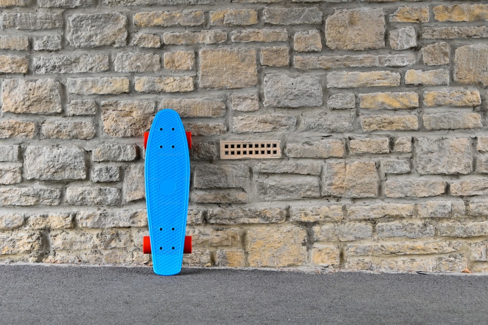 a blue skateboard leaning against a brick wall