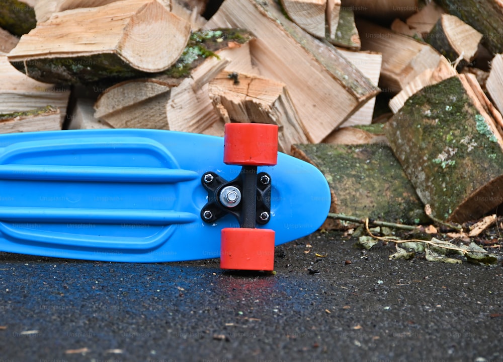 a blue skateboard laying on top of a pile of wood