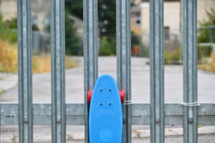 a blue skateboard leaning against a metal fence