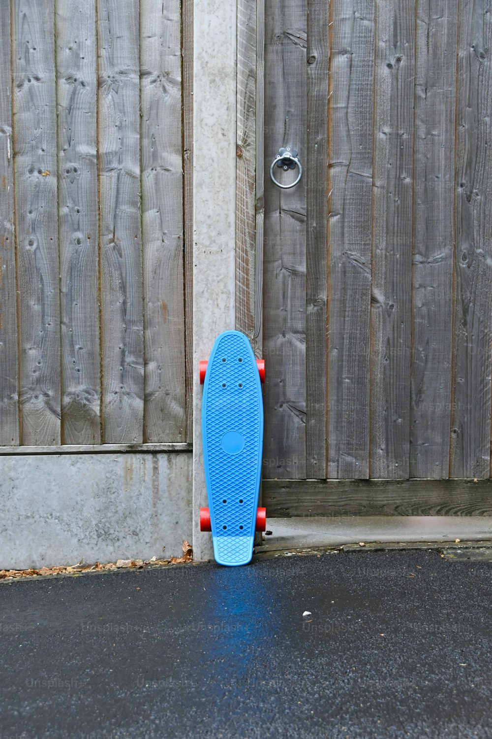 a blue skateboard leaning against a wooden fence