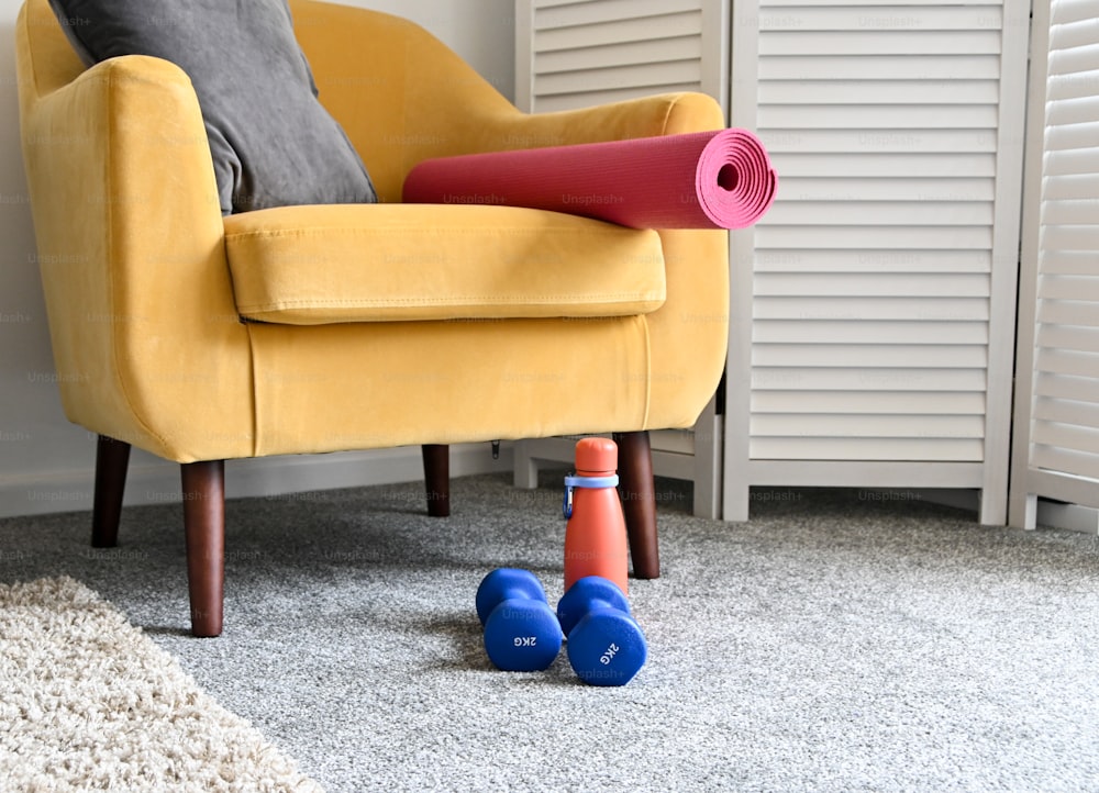 una sedia gialla con un tappetino rosso e due coni blu sul pavimento