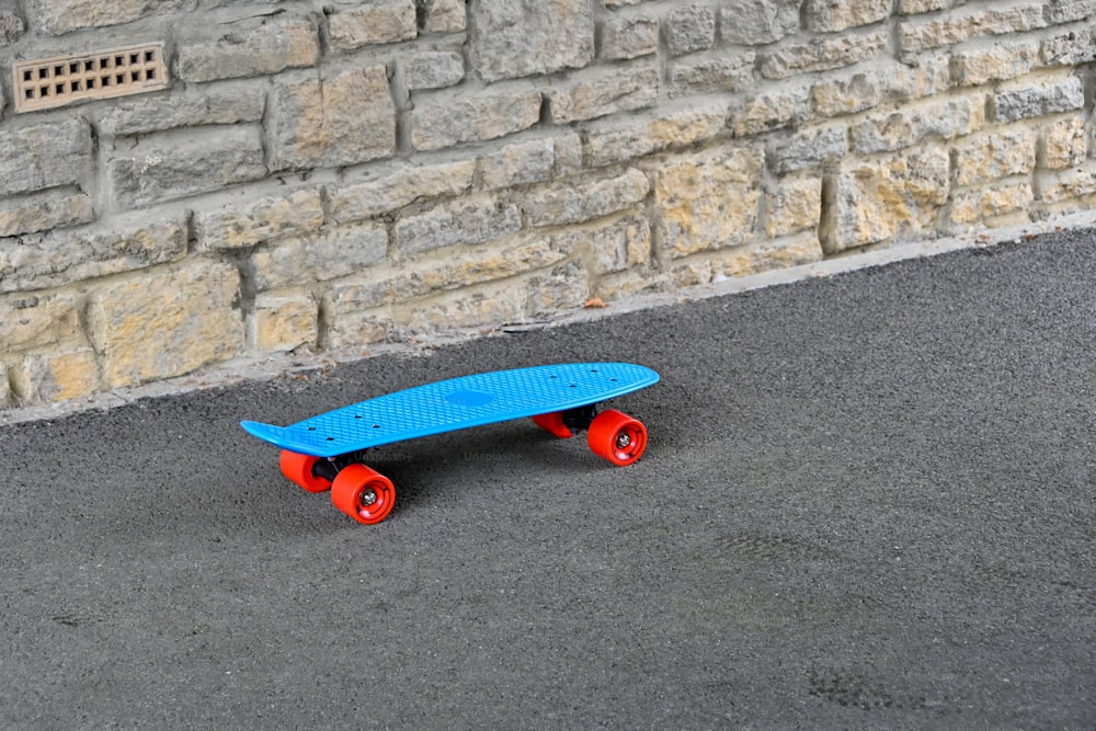 uno skateboard blu seduto di fronte a un muro di mattoni