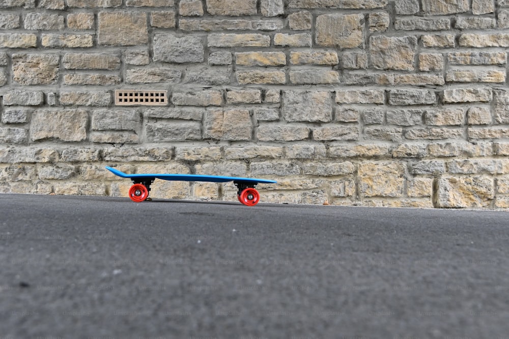 a blue skateboard sitting in front of a brick wall