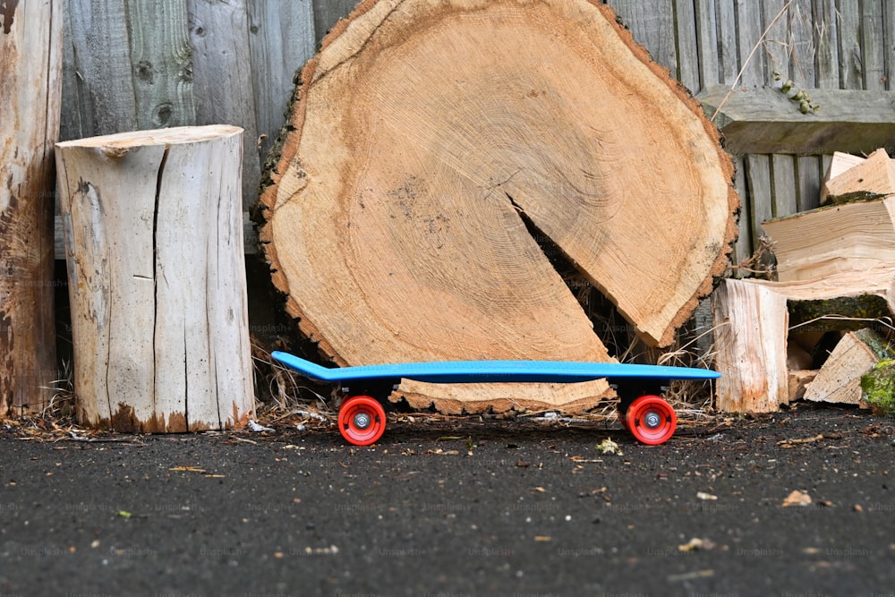 a blue skateboard sitting next to a pile of wood
