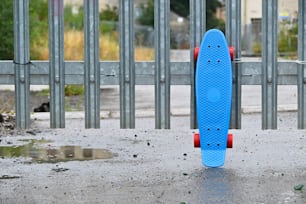 a blue skateboard sitting in front of a metal fence