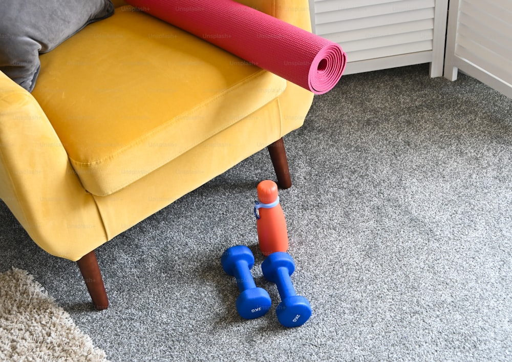 uma cadeira amarela com um tapete de ioga rosa no chão