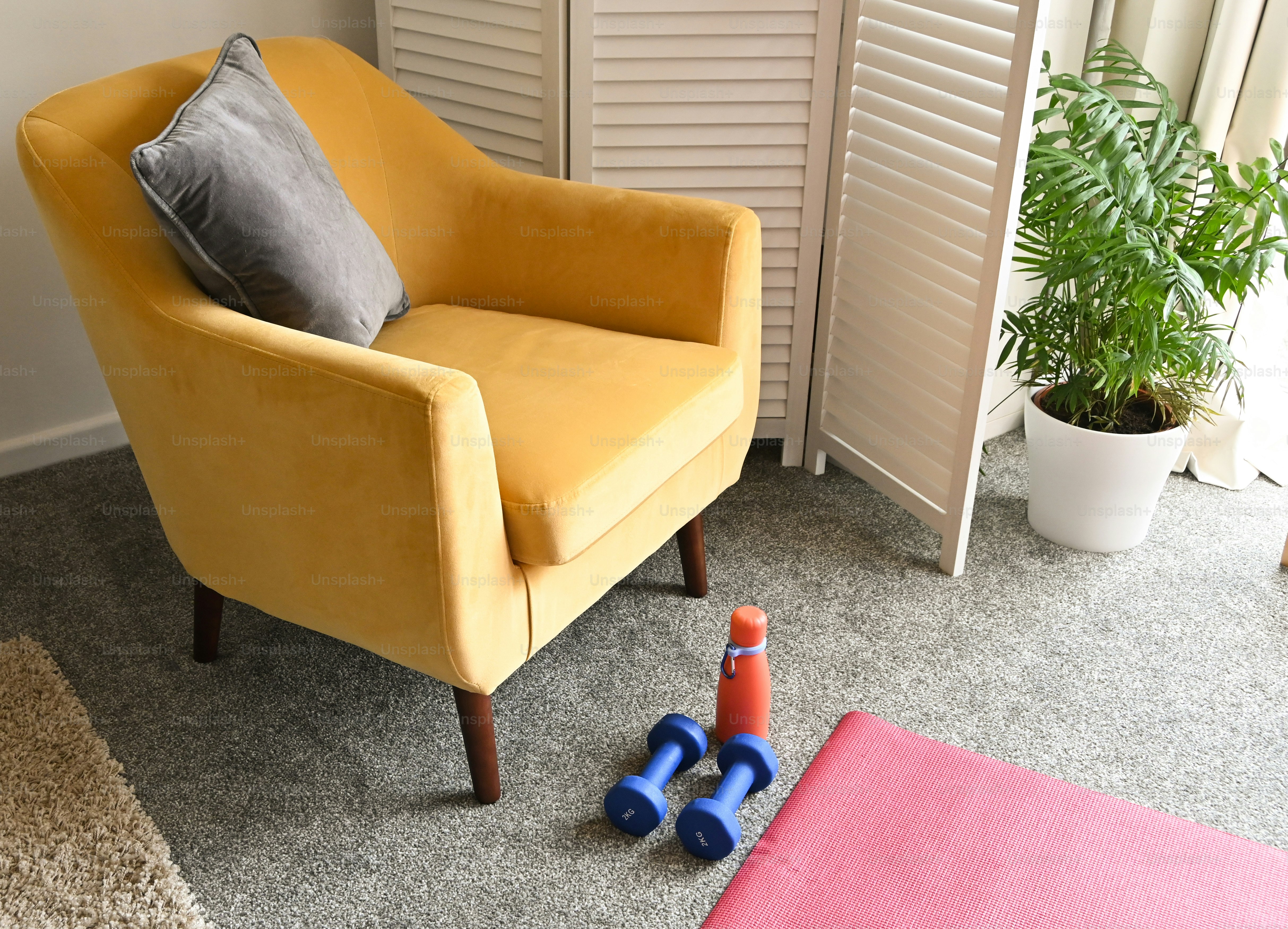 a yellow chair sitting in a living room next to a potted plant