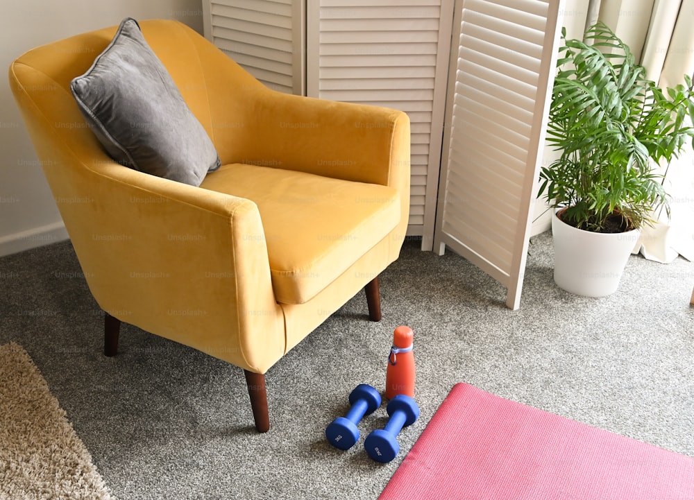 a yellow chair sitting in a living room next to a potted plant