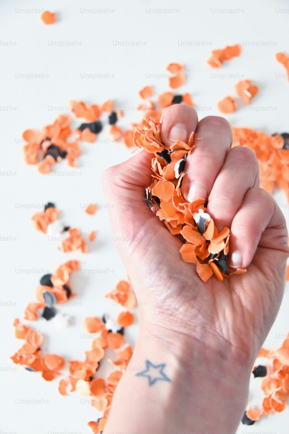 uma mão segurando um punhado de confetes laranja e preto
