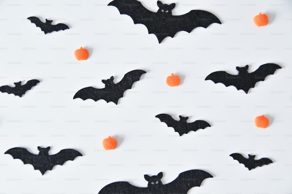 um prato branco coberto com morcegos pretos e doces laranjas