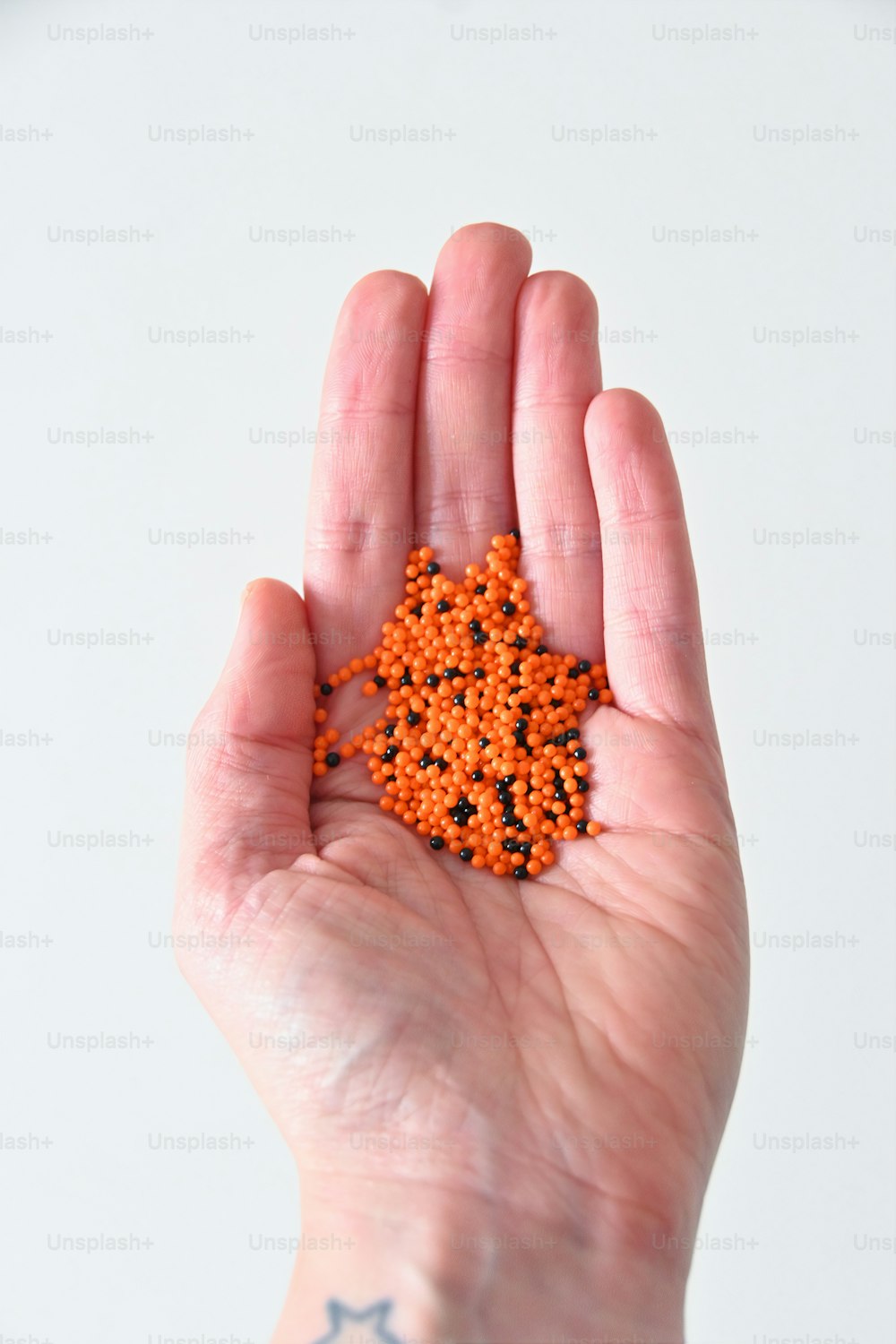 eine Hand, die ein winziges orangefarbenes Objekt in ihrer Handfläche hält
