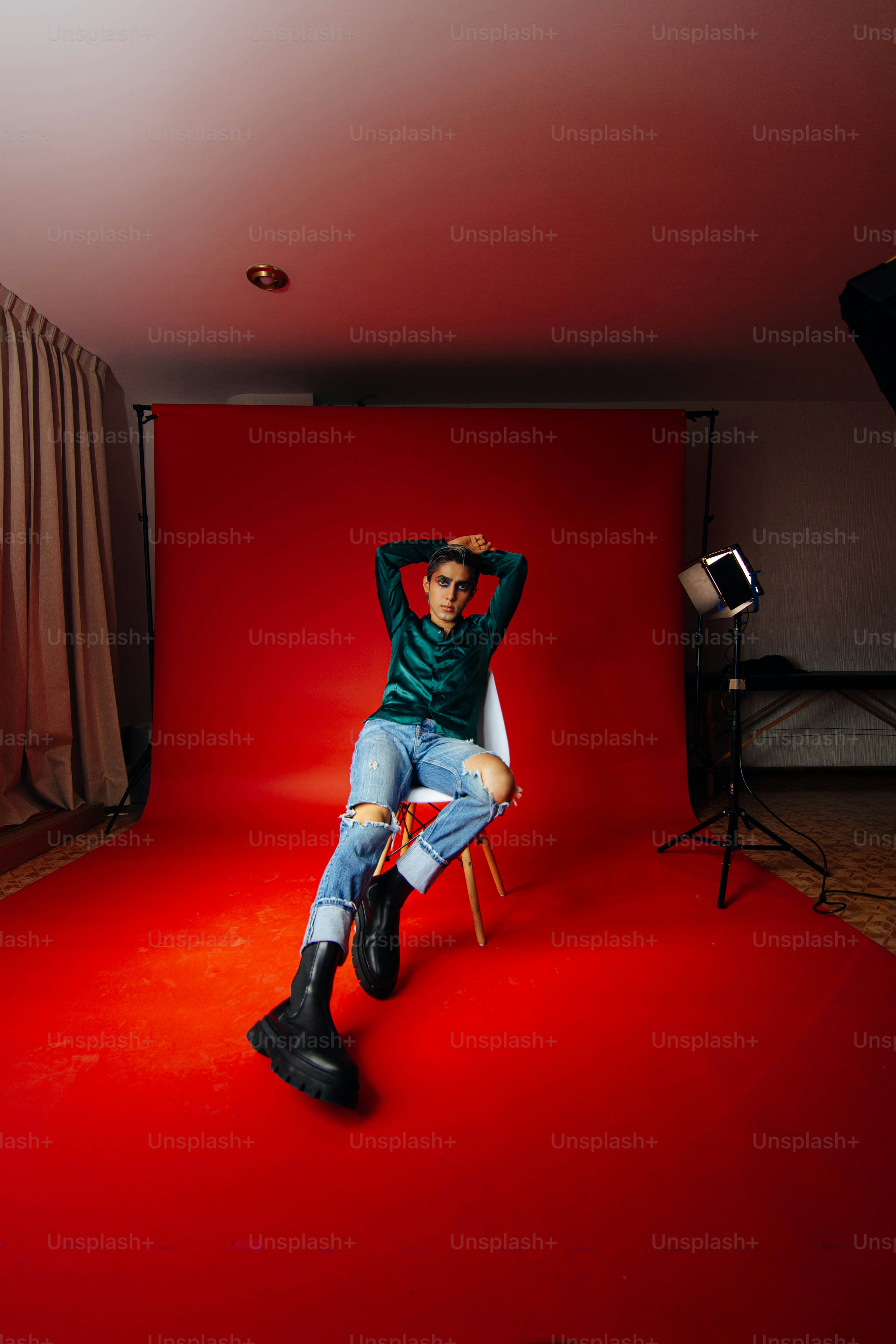 um homem sentado em uma cadeira em frente a um fundo vermelho