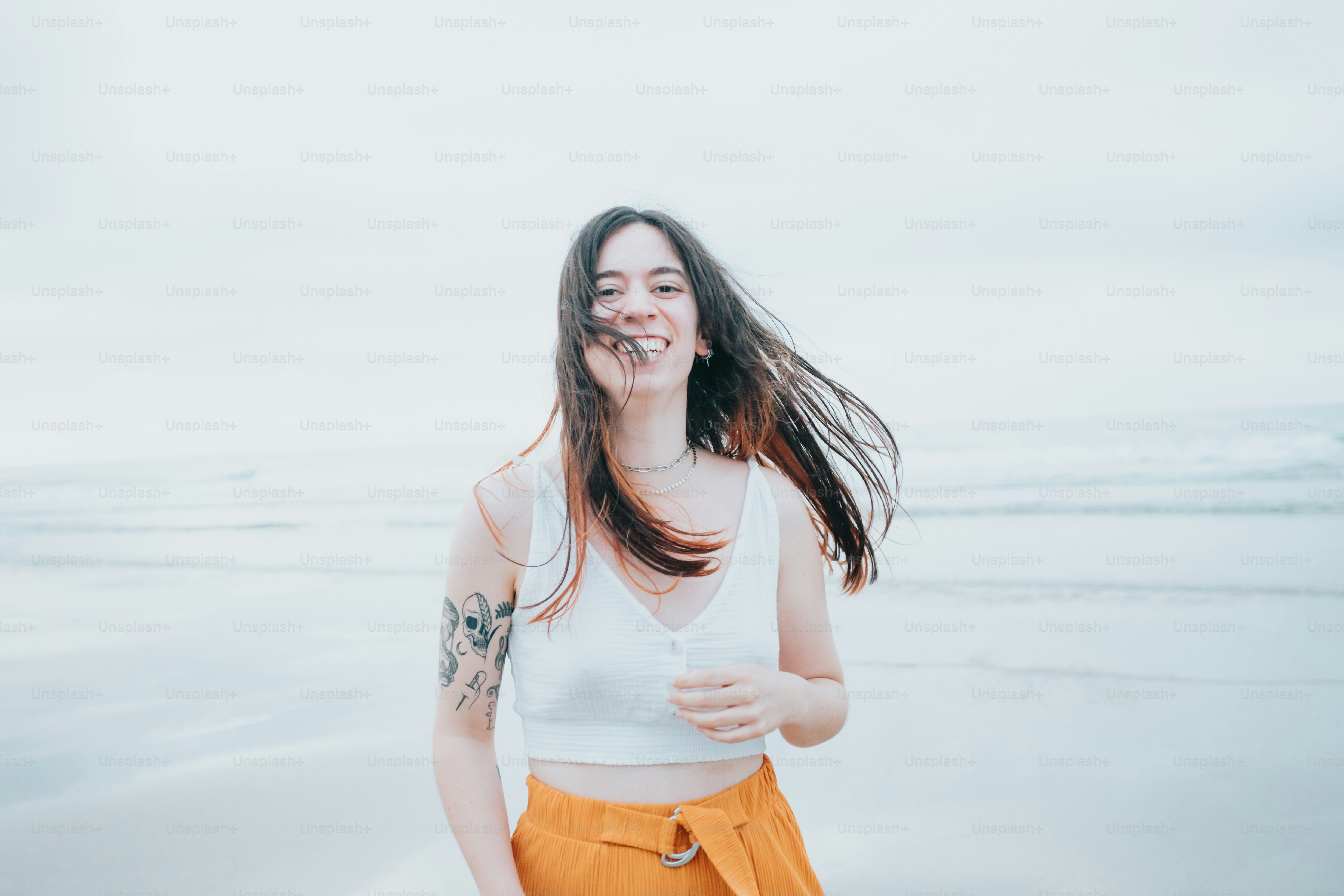 A woman standing on top of a beach next to the ocean photo – Woman ...
