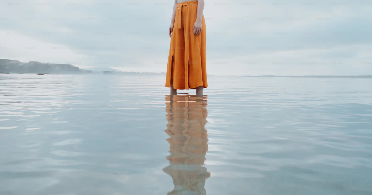 A woman standing in the middle of a body of water photo – Distorted ...