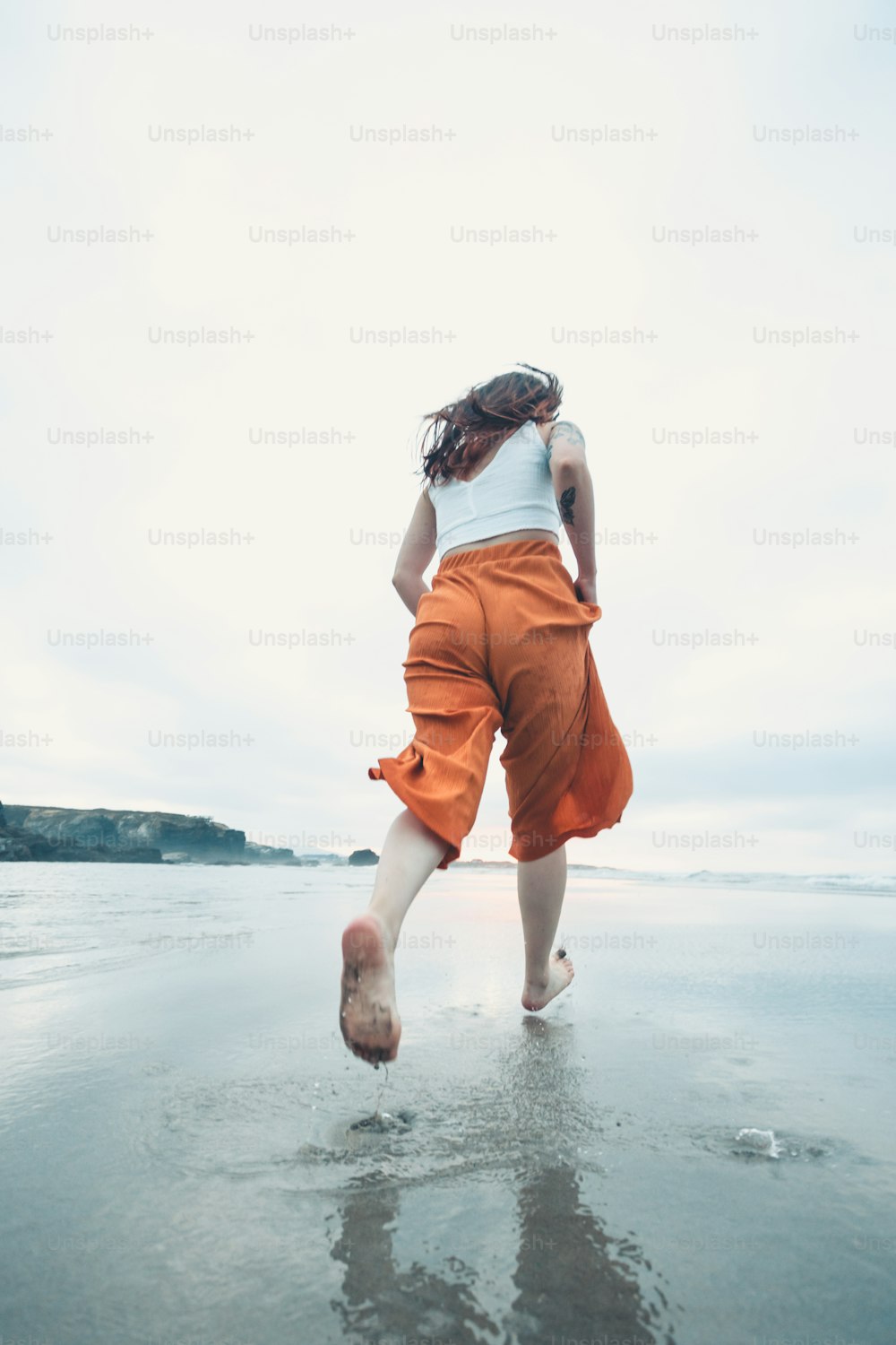 a woman is running on the beach with her feet in the water