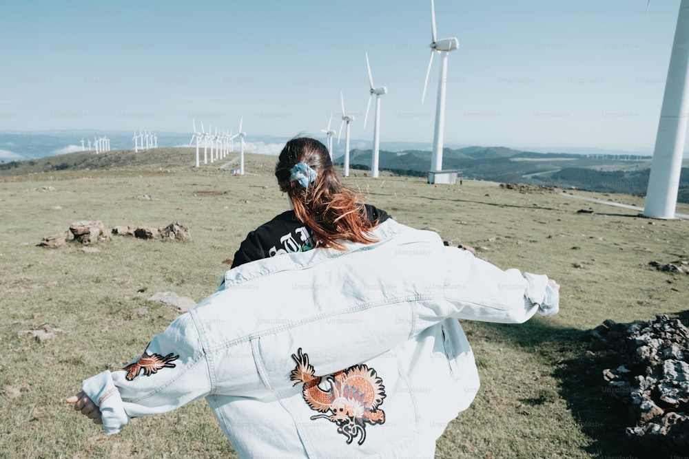 a woman in a white jacket and a wind turbine in the background