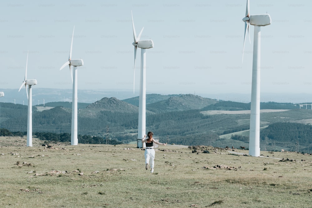 a woman standing in a field of wind turbines