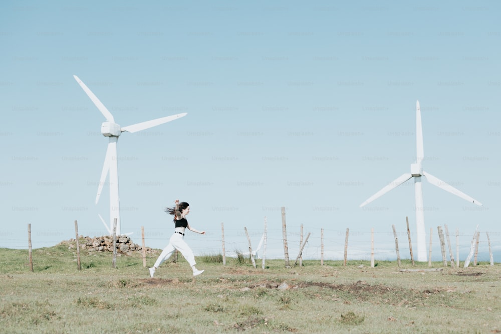 a woman running in a field with wind turbines in the background