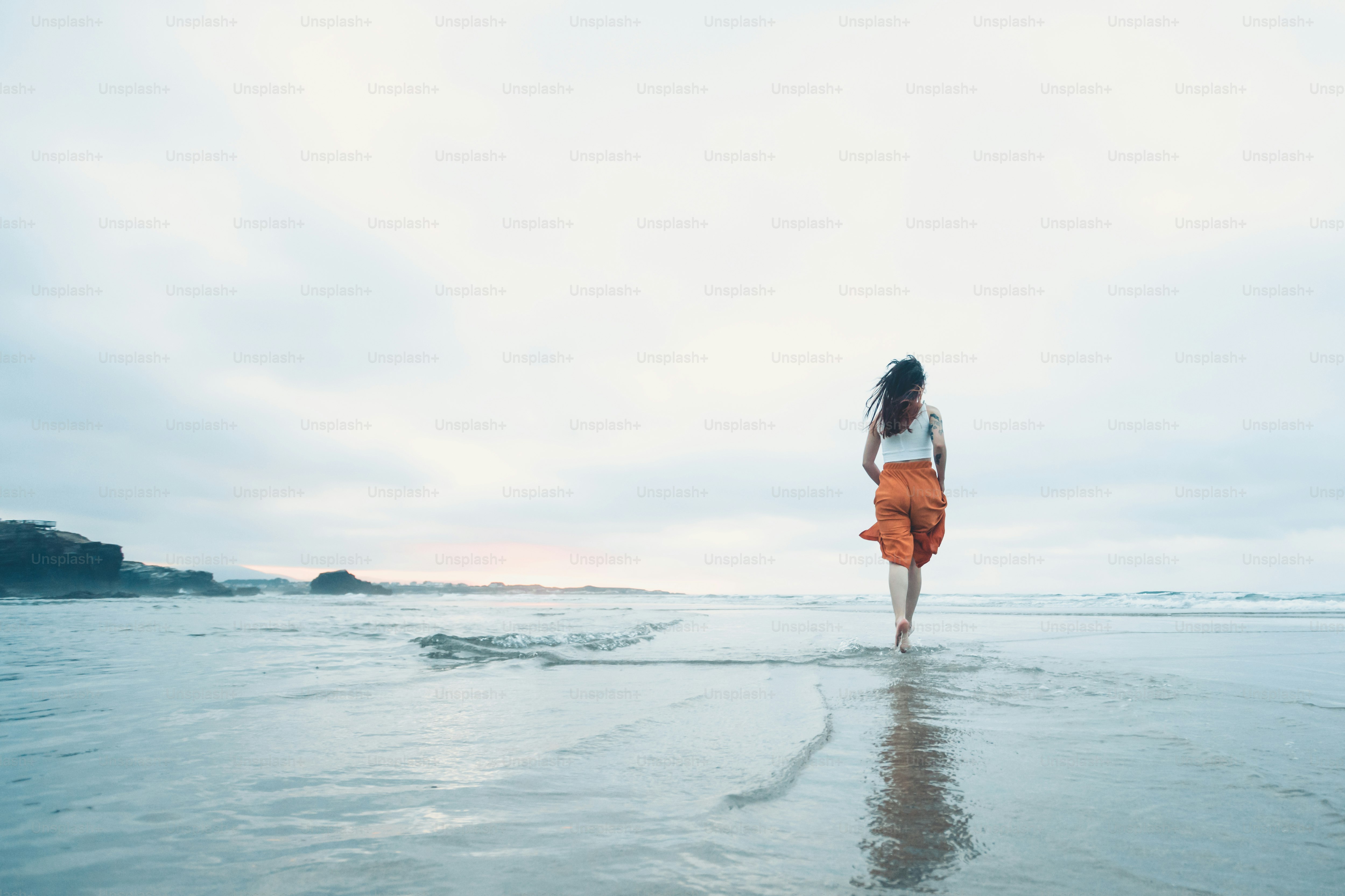 A woman walking on the beach in the water photo – Waves Image on Unsplash
