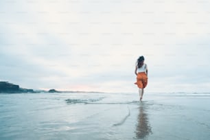 a woman walking on the beach in the water