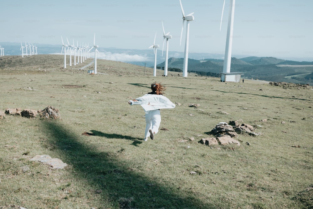 eine Person auf einem Feld mit Windkraftanlagen im Hintergrund