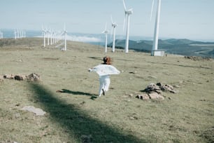 a person in a field with wind turbines in the background