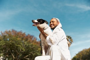 Un hombre sosteniendo un perro blanco y negro en sus brazos
