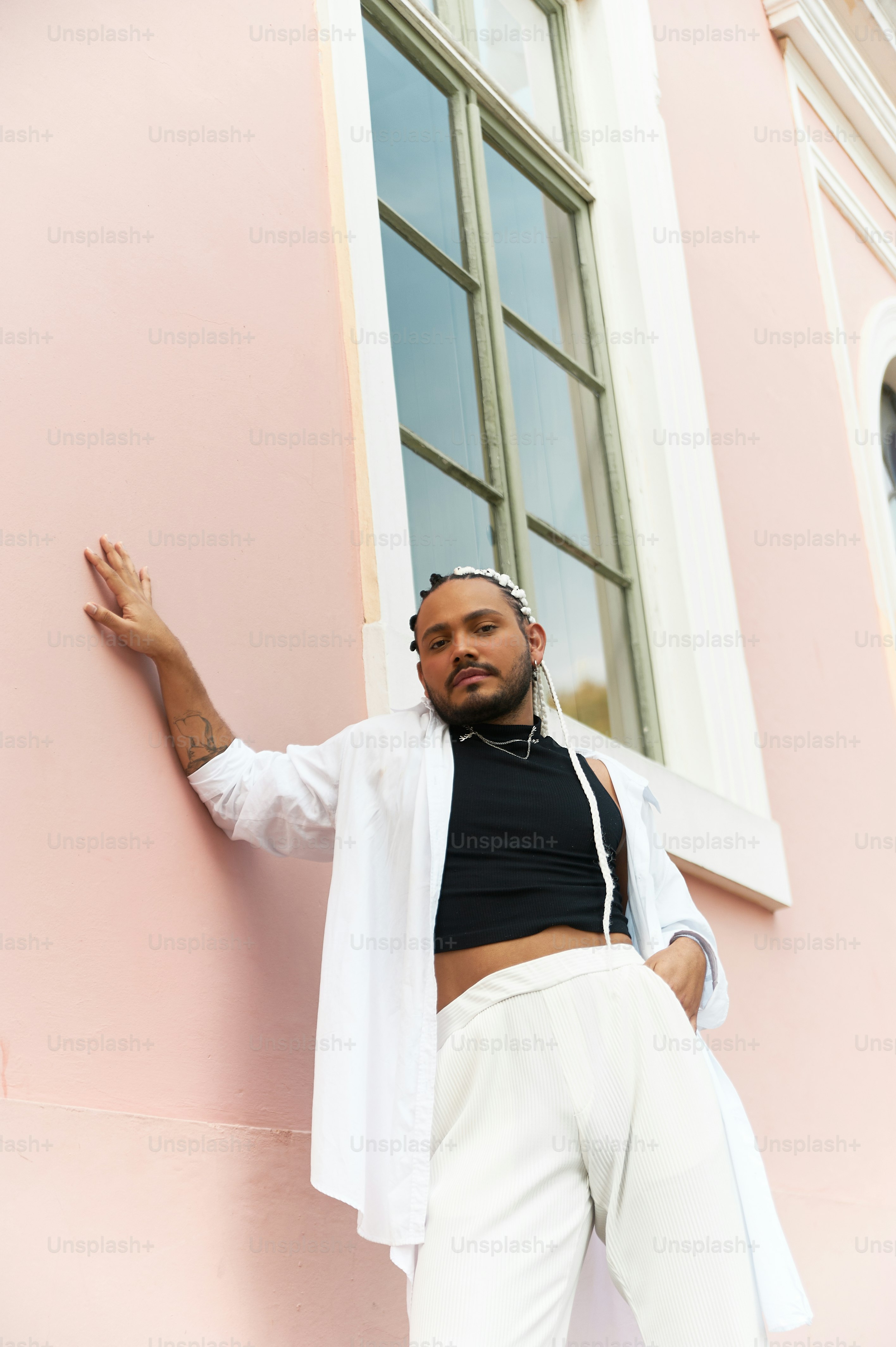 a man leaning up against a pink building