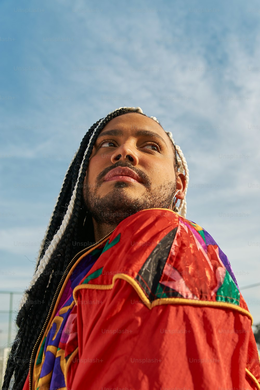 a man with dreadlocks standing in front of a blue sky